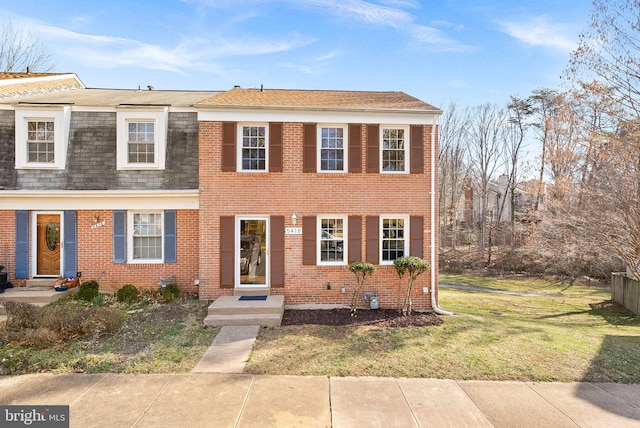 view of front of property featuring brick siding, a front yard, and roof with shingles