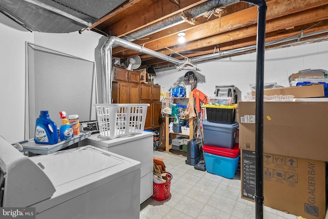 unfinished below grade area with concrete block wall, light floors, and washing machine and clothes dryer