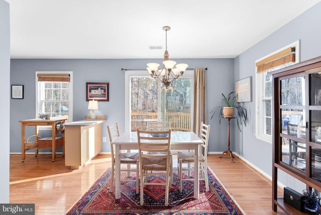 dining area featuring visible vents, baseboards, an inviting chandelier, and wood finished floors