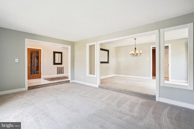 spare room with a notable chandelier, visible vents, and carpet