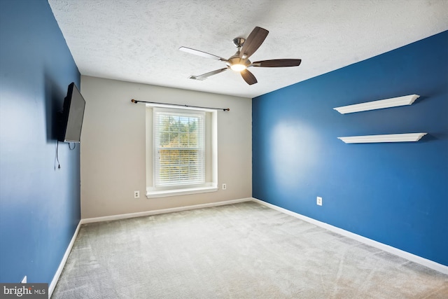carpeted spare room with baseboards, a textured ceiling, and ceiling fan
