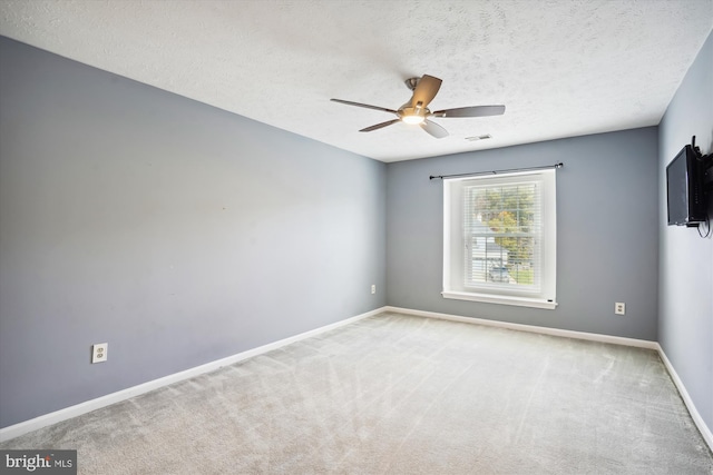 carpeted spare room featuring ceiling fan, baseboards, a textured ceiling, and visible vents