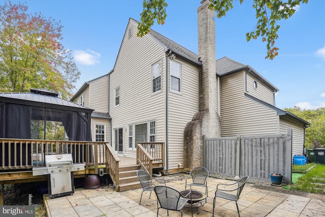 back of house with a gazebo, a patio area, a chimney, an outdoor fire pit, and a wooden deck
