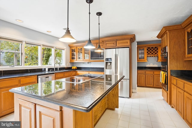 kitchen featuring brown cabinetry, appliances with stainless steel finishes, a center island, and a sink