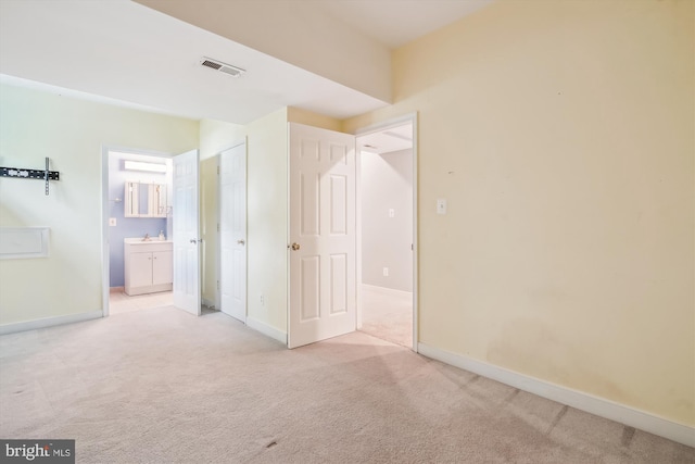 unfurnished bedroom with light colored carpet, baseboards, connected bathroom, and visible vents