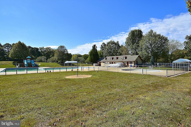view of yard with a community pool, fence, and playground community