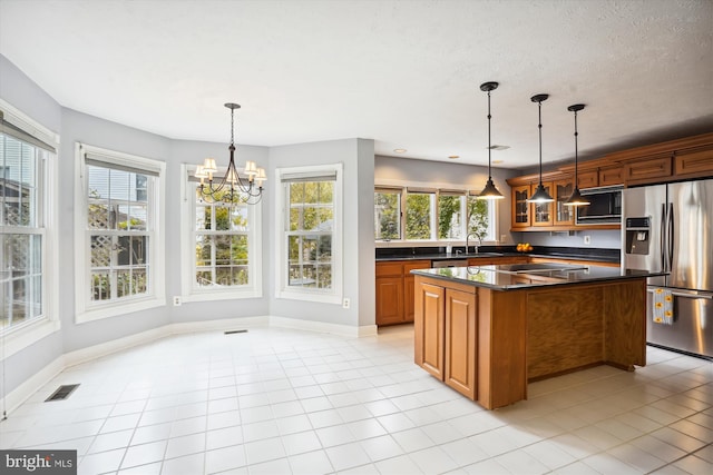 kitchen with dark countertops, a sink, a chandelier, stainless steel fridge, and visible vents