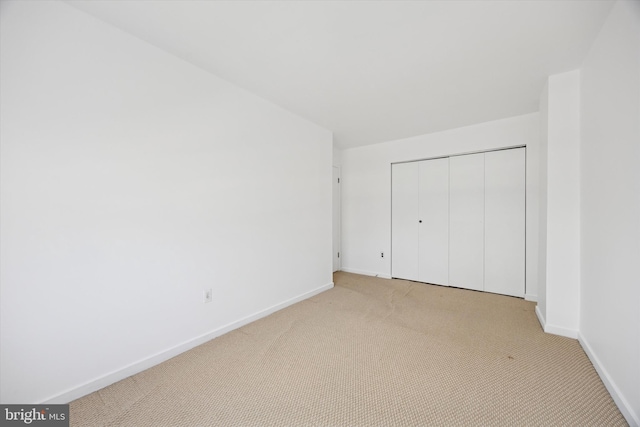 unfurnished bedroom featuring a closet, baseboards, and light colored carpet