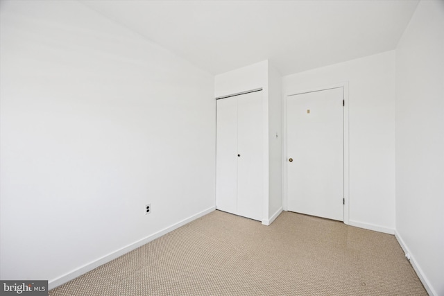 unfurnished bedroom featuring a closet, baseboards, and light carpet