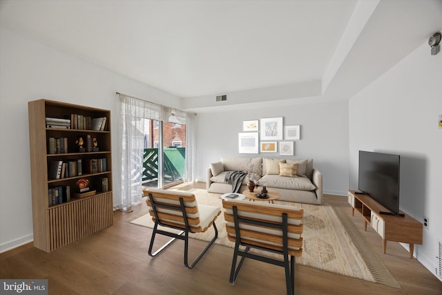 living room with wood finished floors, visible vents, and baseboards