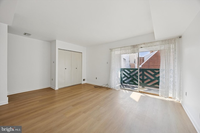 unfurnished bedroom featuring a closet, visible vents, baseboards, and wood finished floors