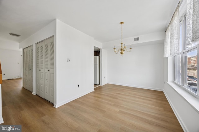 unfurnished dining area with visible vents, baseboards, light wood finished floors, and a chandelier