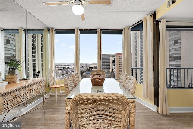 dining space with wood finished floors, visible vents, baseboards, ceiling fan, and floor to ceiling windows