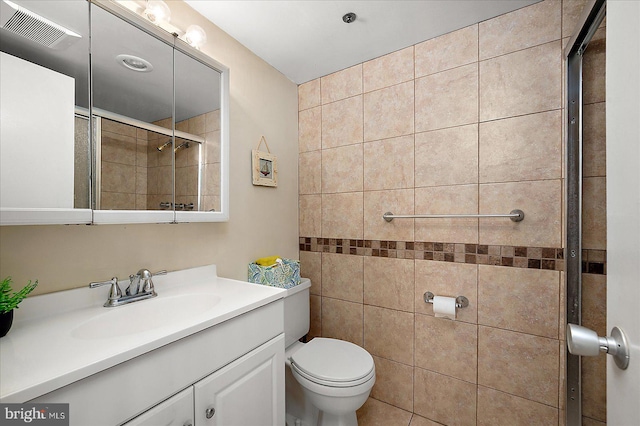 bathroom featuring visible vents, tiled shower, toilet, and vanity