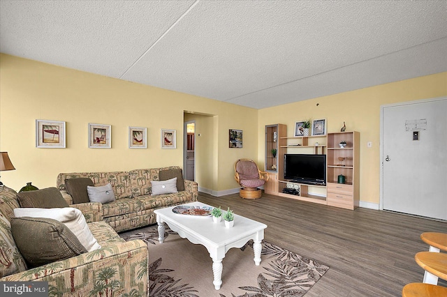 living area with baseboards, a textured ceiling, and wood finished floors