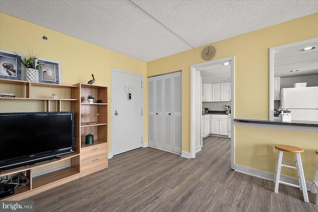 living area with baseboards, dark wood-type flooring, and a textured ceiling