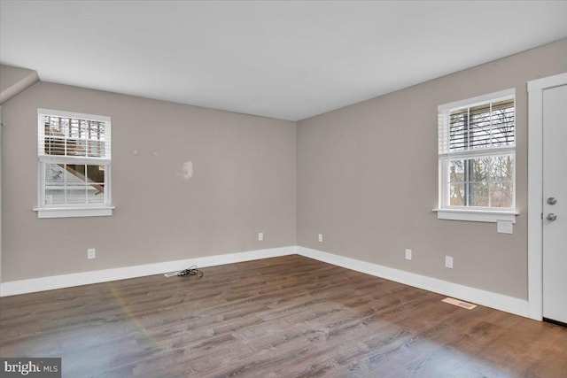 spare room with visible vents, wood finished floors, and baseboards