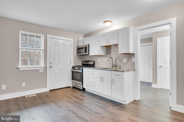 kitchen featuring a sink, wood finished floors, visible vents, and stainless steel appliances