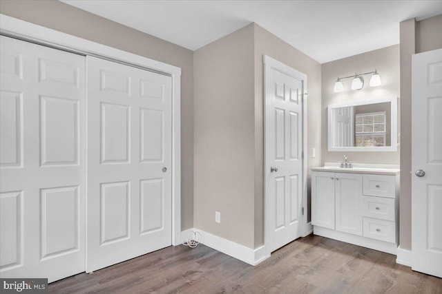 bathroom with baseboards, wood finished floors, and vanity