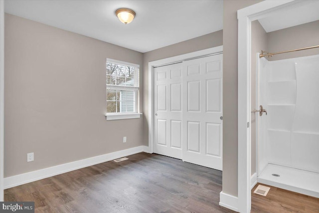 unfurnished bedroom with visible vents, baseboards, a closet, and wood finished floors