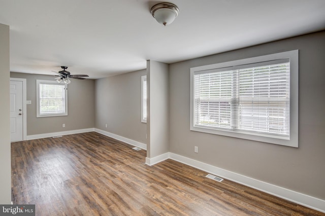 unfurnished room with a ceiling fan, visible vents, wood finished floors, and baseboards