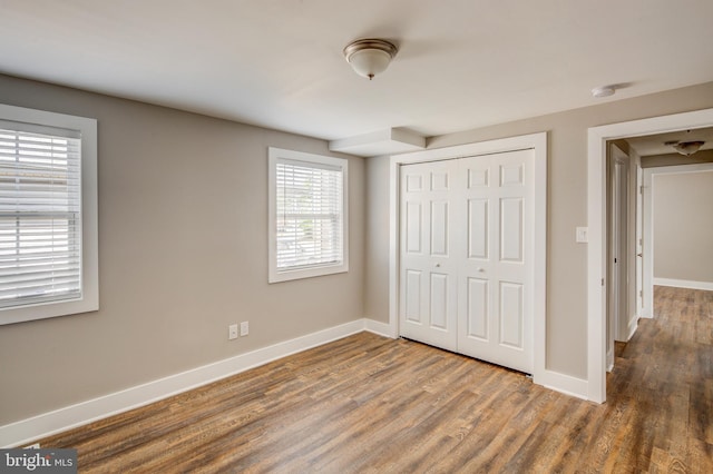 unfurnished bedroom with a closet, baseboards, and wood finished floors