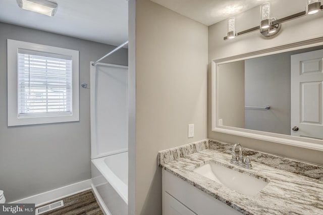 full bath featuring visible vents, wood finished floors, shower / bathing tub combination, baseboards, and vanity