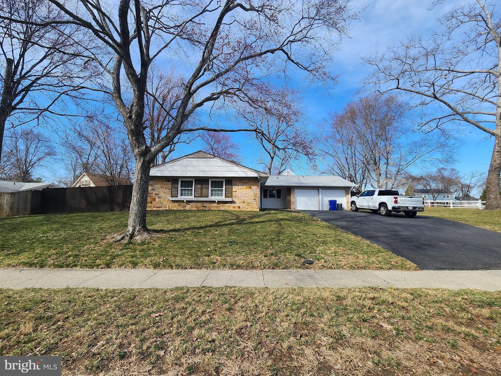 view of front of home featuring aphalt driveway, an attached garage, a front yard, and fence