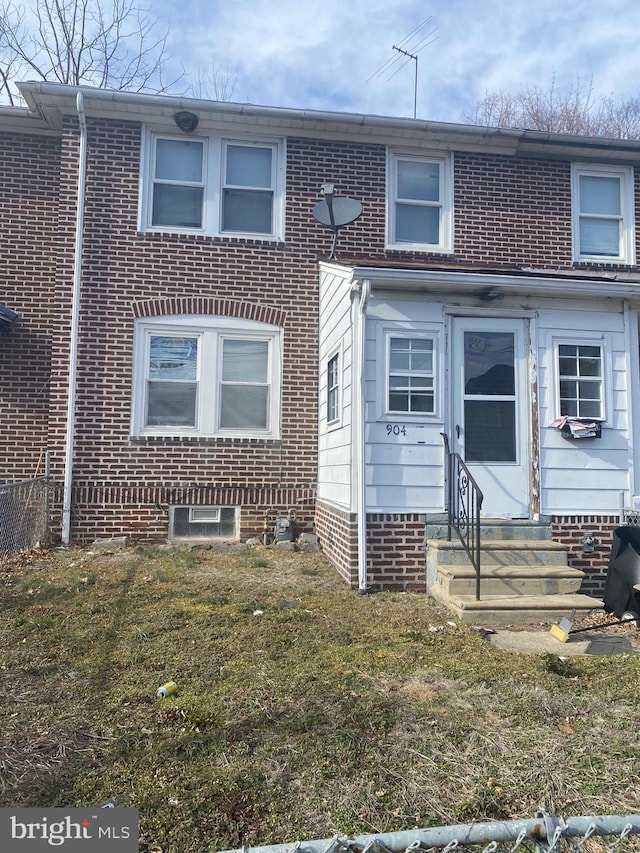 multi unit property featuring brick siding, entry steps, and a front lawn