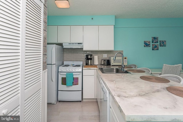 kitchen featuring under cabinet range hood, white cabinets, white appliances, and a peninsula