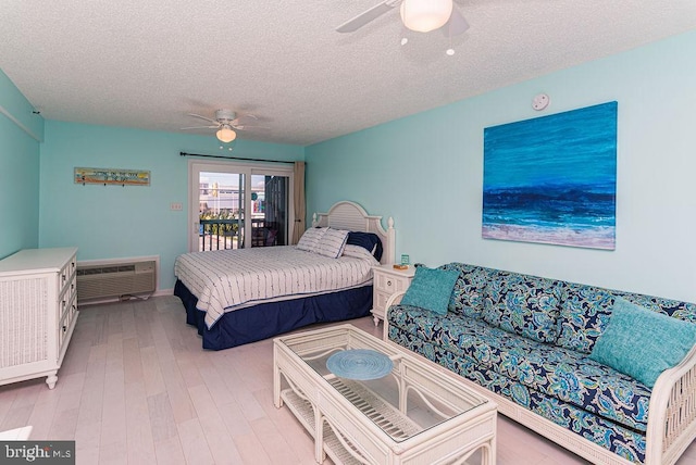 bedroom with a ceiling fan, a wall unit AC, access to outside, and wood finished floors