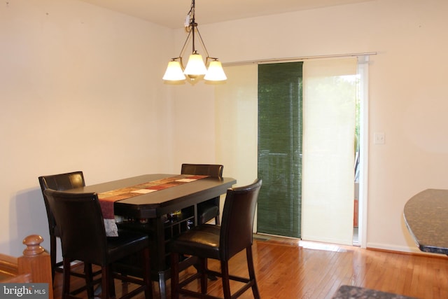 dining room with a notable chandelier, baseboards, and hardwood / wood-style floors