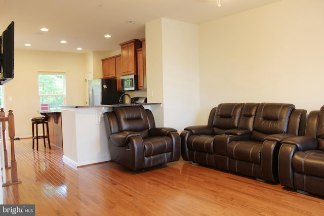 living room with recessed lighting, baseboards, and light wood-style flooring