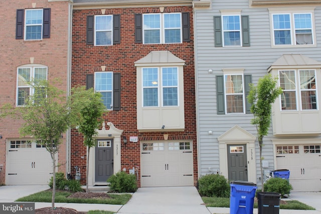 townhome / multi-family property with brick siding, driveway, and an attached garage