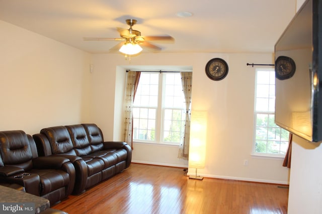 living area featuring baseboards, a healthy amount of sunlight, a ceiling fan, and hardwood / wood-style flooring