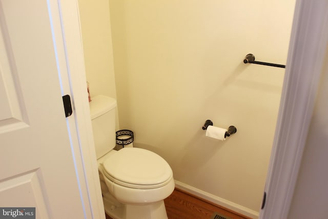 bathroom with baseboards, toilet, and wood finished floors