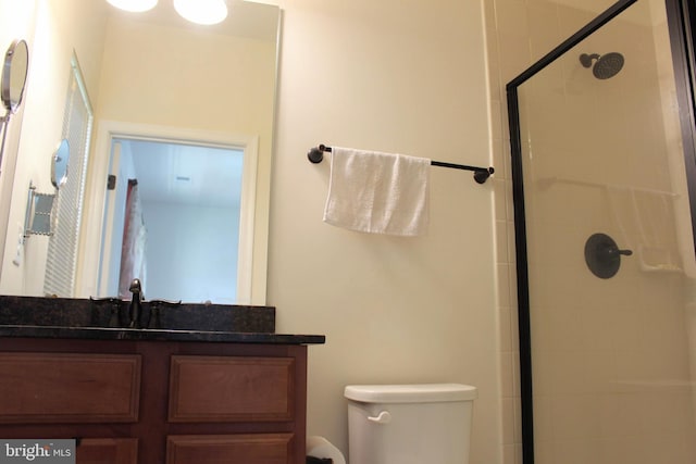 bathroom with a shower stall, toilet, and vanity