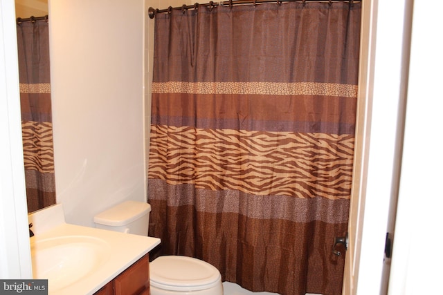 full bath featuring a shower with shower curtain, toilet, and vanity