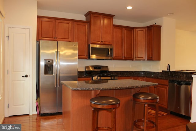 kitchen featuring a kitchen island, dark wood-type flooring, a breakfast bar area, recessed lighting, and appliances with stainless steel finishes