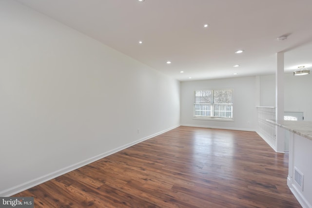 empty room with dark wood-type flooring, recessed lighting, visible vents, and baseboards