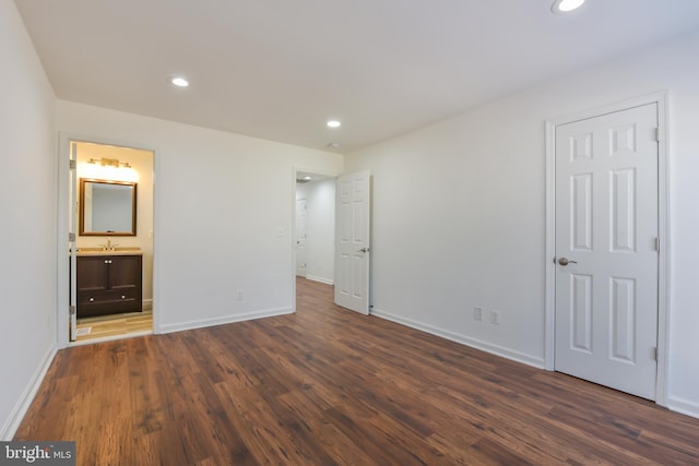 unfurnished bedroom featuring recessed lighting, ensuite bath, dark wood-type flooring, and baseboards