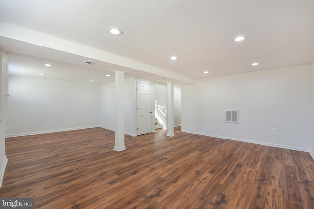 finished basement featuring dark wood finished floors, visible vents, recessed lighting, and stairs