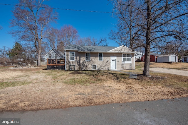 view of front of property featuring a wooden deck, a front lawn, and a shingled roof