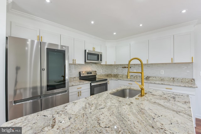 kitchen with ornamental molding, a sink, backsplash, white cabinetry, and appliances with stainless steel finishes