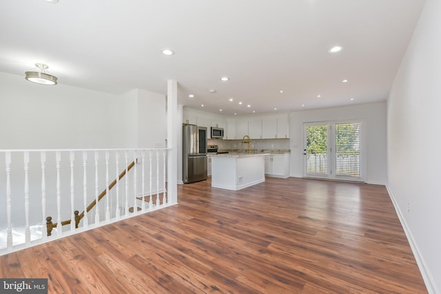 kitchen featuring backsplash, open floor plan, stainless steel appliances, white cabinets, and dark wood-style flooring