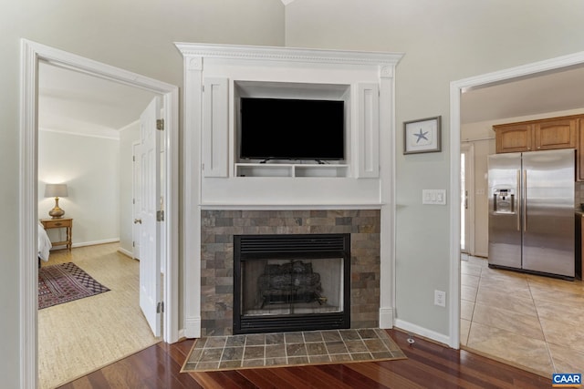 living room featuring a tile fireplace, baseboards, and wood finished floors