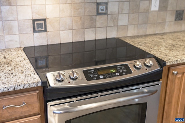 details featuring brown cabinets, backsplash, stainless steel range with electric stovetop, and light stone countertops