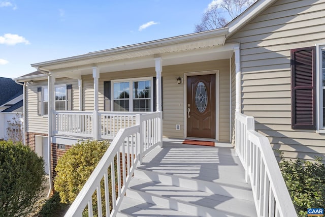 view of exterior entry with brick siding and covered porch