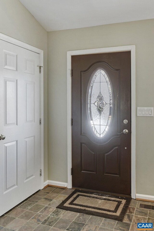 entrance foyer featuring baseboards and stone finish flooring