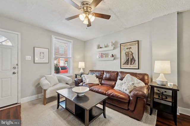 living room with wood finished floors, baseboards, a textured ceiling, and ceiling fan